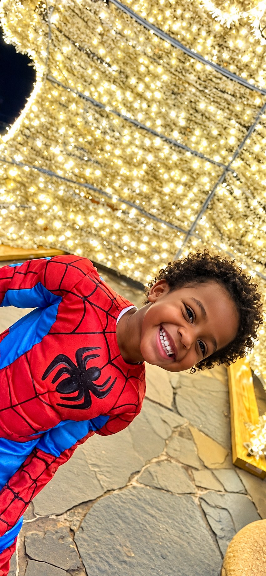 Chaston Florence smiling in a Spider-Man costume under holiday lights